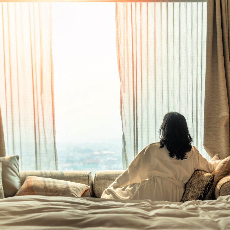 Woman-Looks-OUt-Window-Of-Luxury-Hotel-Room-Bali-Ocean-View