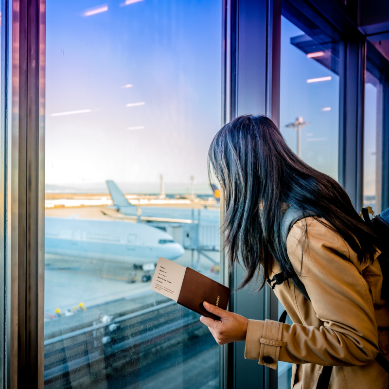 Woman-looks-at-plane-with-passport-in-her-hand-at-airport-