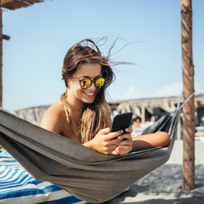 Woman-on-Phone-on-Beach-in-Hammock
