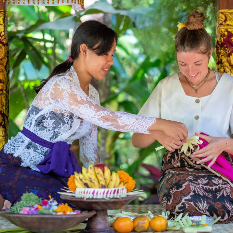 Balinese-Woman-Teaches-Tourist-to-make-Canang-Sari-in-Bali