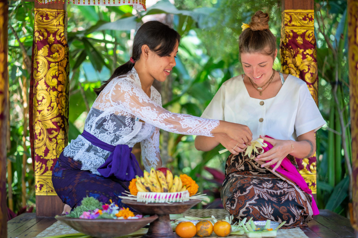 Balinese Woman Teaches Tourist to make Canang Sari in Bali.jpg