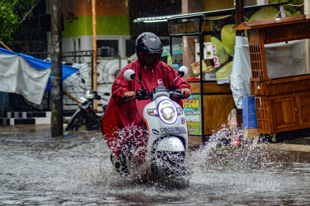 Moped Driver Drives Thorugh Rain and Flooded Road in Bali.jpg