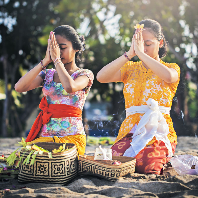 Two-Balinese-Women-Pray-On-Bali-Beach