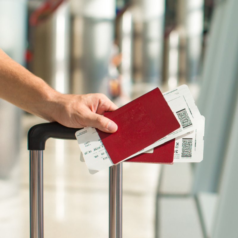 Two Passports in Hand On Luggage At Airport.jpg