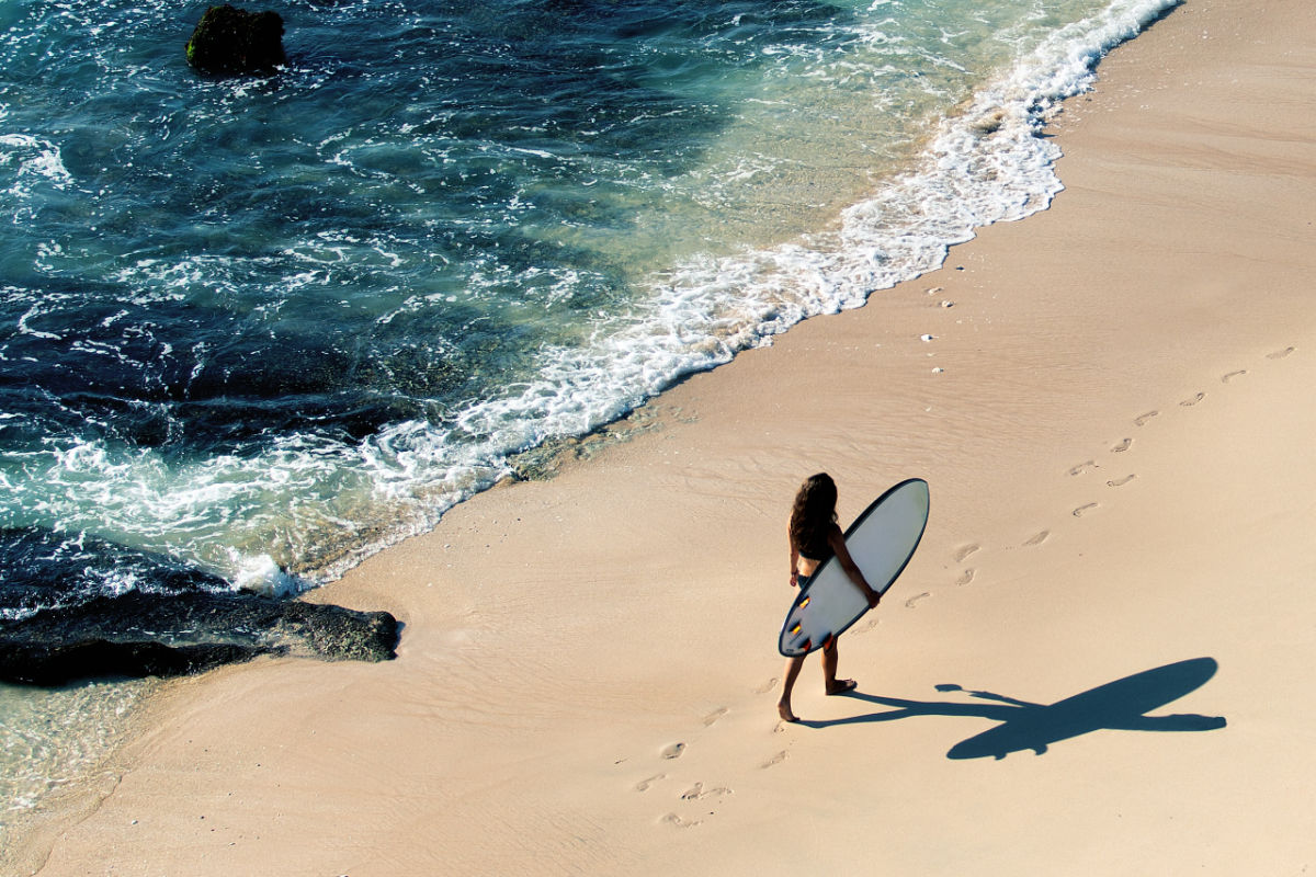 Woman Walks Along Beach With Surfboard.jpg