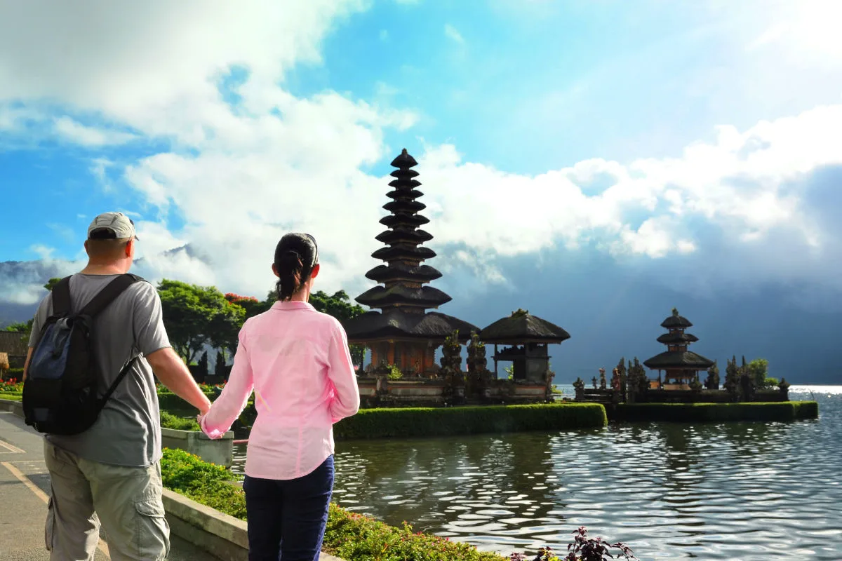 Tourists Stand Hand in Hand Looking at Temple in Bedugul