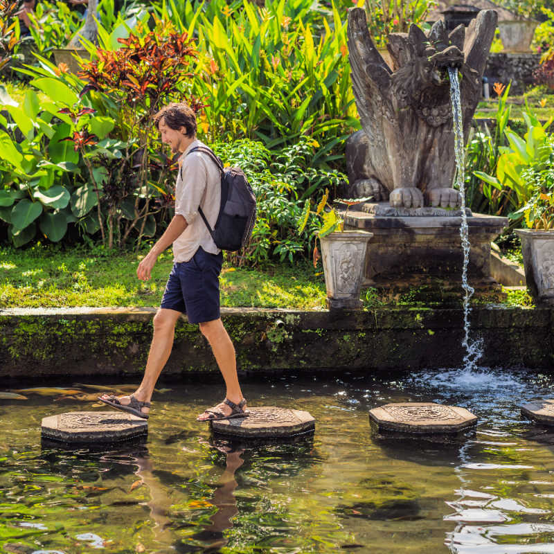 Man Walks Over Stepping Stones At Tirta Gangga East Bali