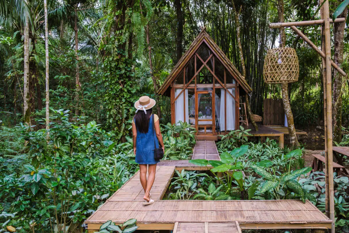 Woman Tourist Walks Towards Eco-Stay Hotel Resort In Bali.jpg
