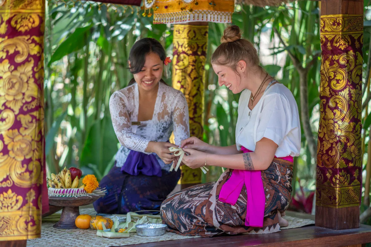 Balinese Woman and Tourist Make Canang Sari.jpg