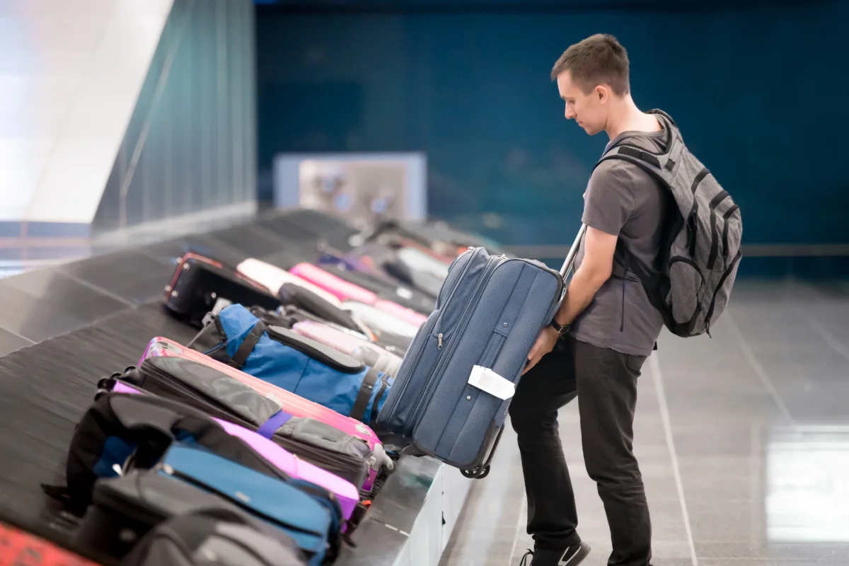 Man Stands by Luggage Carousel at Airport.jpg