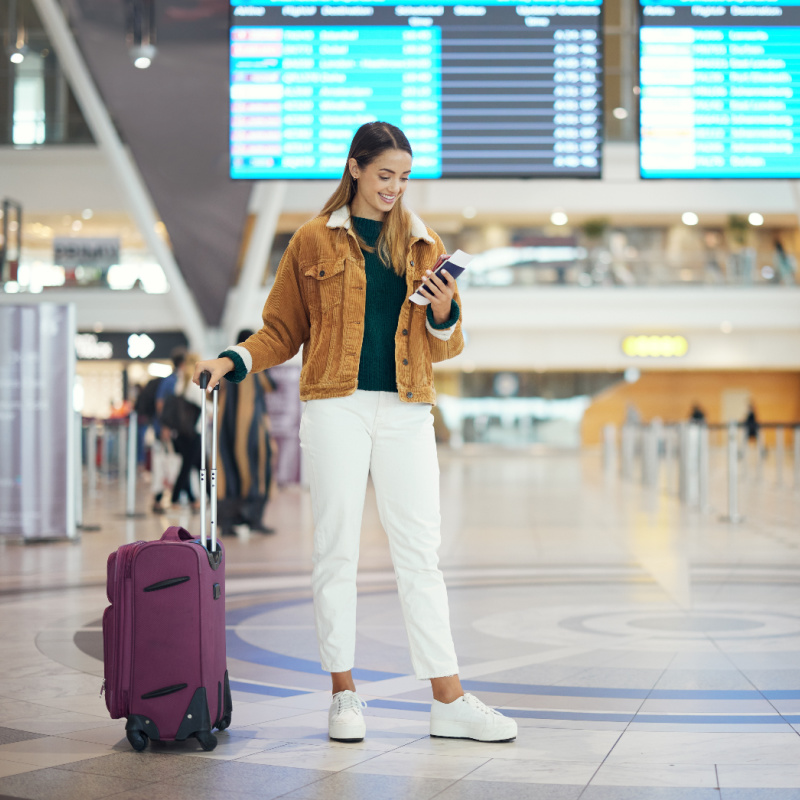 Female Traveler Looks at Phone At Airport