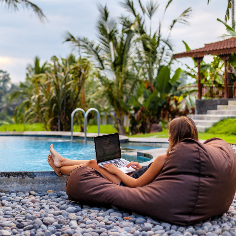Woman on Laptop in Villa Garden in Bali by Pool