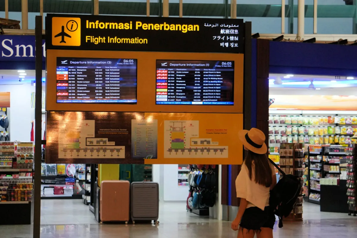 Airport Passenger Looks At Flight Board in Bali Airport.jpg