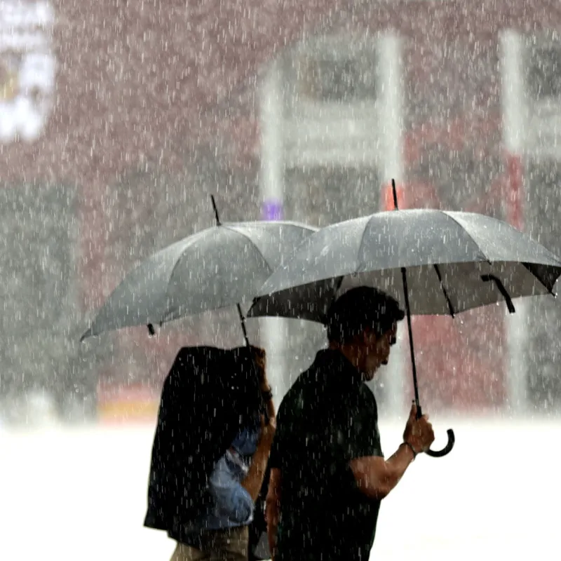Indonesia Bali Weather Rain People Walk With Umbrellas.jpg