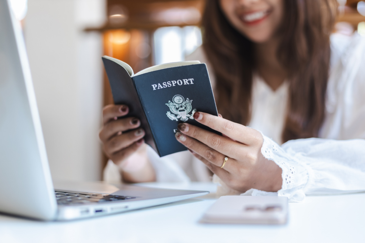 Woman Looks at Passport by Laptop.jpg